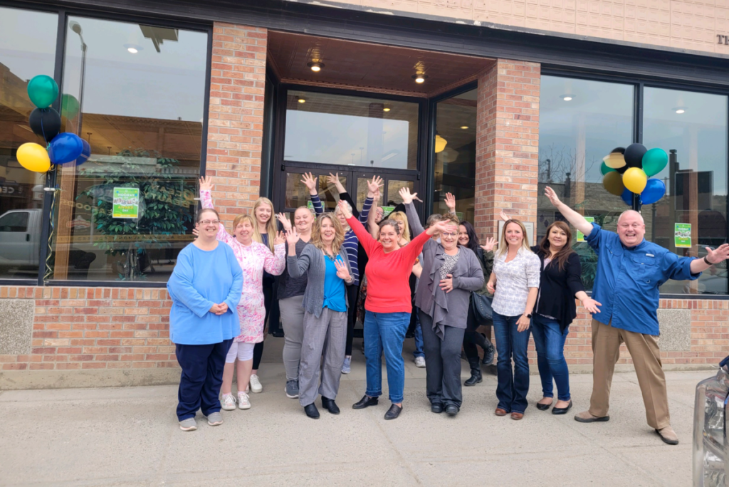 Staff celebrate in front of a building.