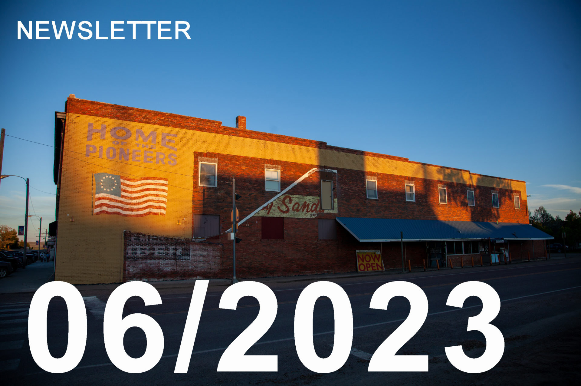 image of an old building in Big Sandy, MT catching the evening sunlight. An American Flag can be seen on the building.